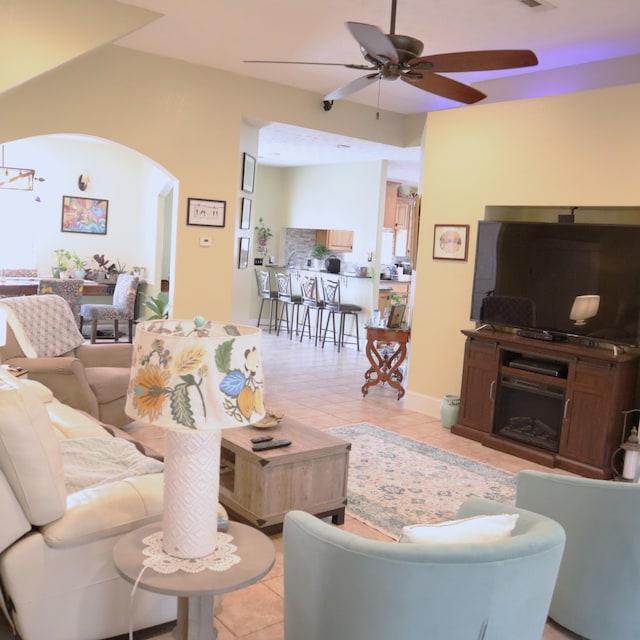 tiled living room featuring a fireplace and ceiling fan