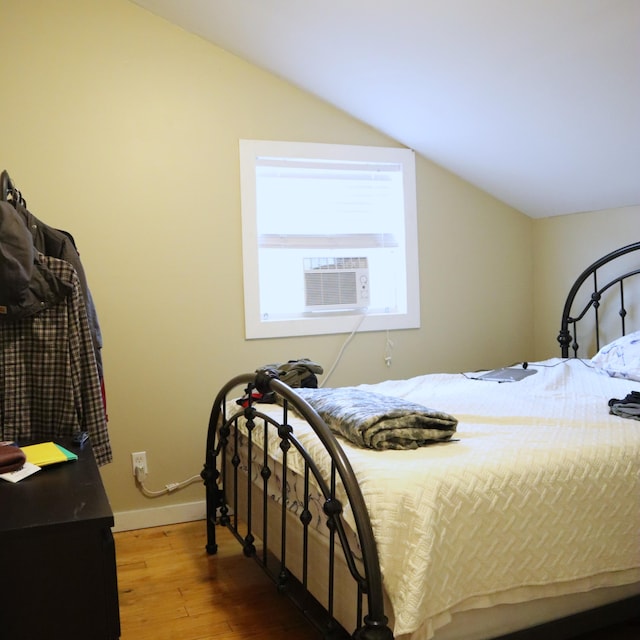 bedroom with hardwood / wood-style flooring, cooling unit, and lofted ceiling