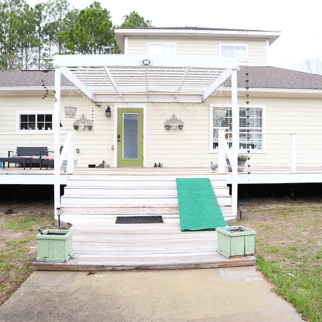 rear view of property featuring a deck and a pergola