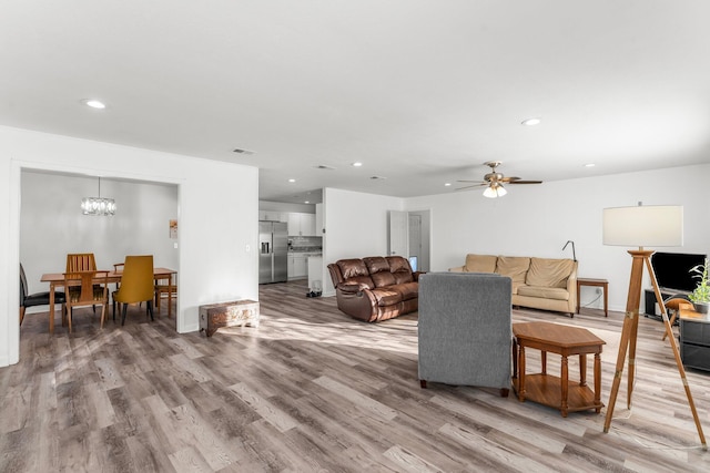 living room featuring hardwood / wood-style floors and ceiling fan with notable chandelier