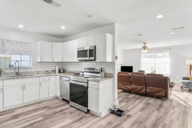 kitchen featuring white cabinetry, sink, light wood-type flooring, and appliances with stainless steel finishes