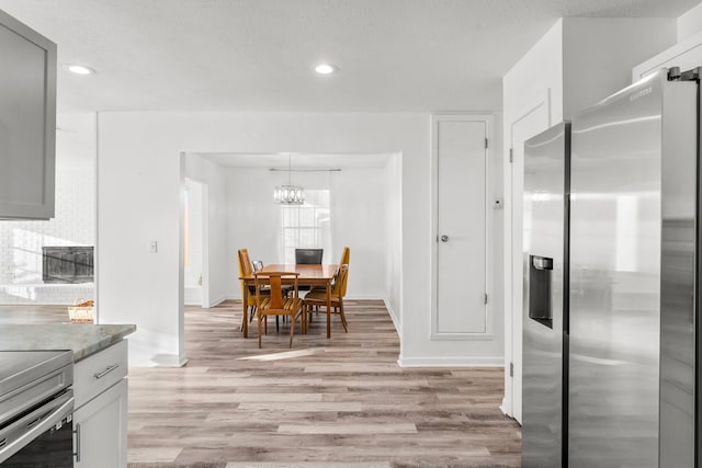 kitchen with gray cabinets, light hardwood / wood-style flooring, stove, and stainless steel refrigerator with ice dispenser