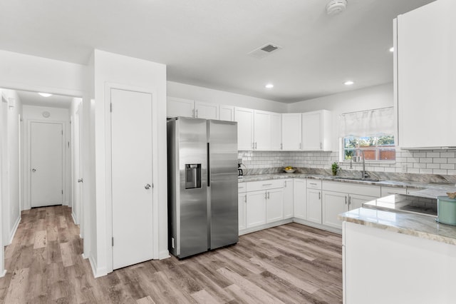 kitchen with stainless steel fridge, white cabinetry, sink, and light hardwood / wood-style flooring