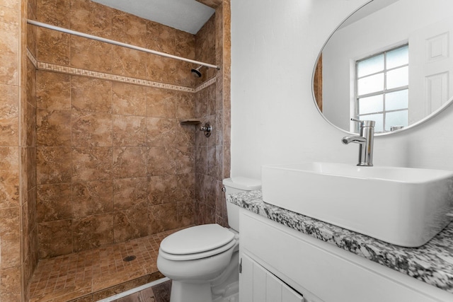 bathroom with tiled shower, vanity, and toilet