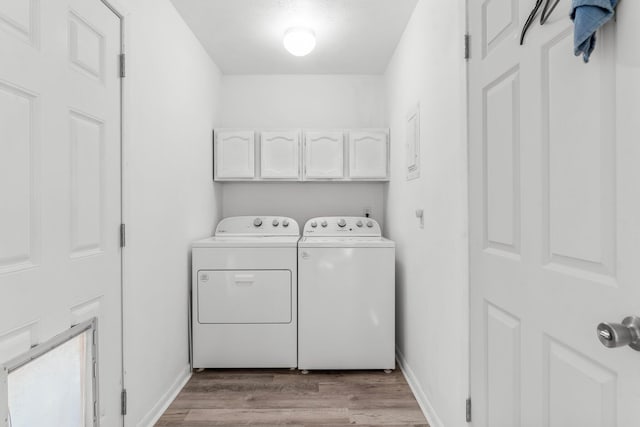 laundry room featuring cabinets, light hardwood / wood-style floors, and washer and clothes dryer