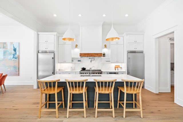 kitchen featuring decorative backsplash, an island with sink, and built in refrigerator