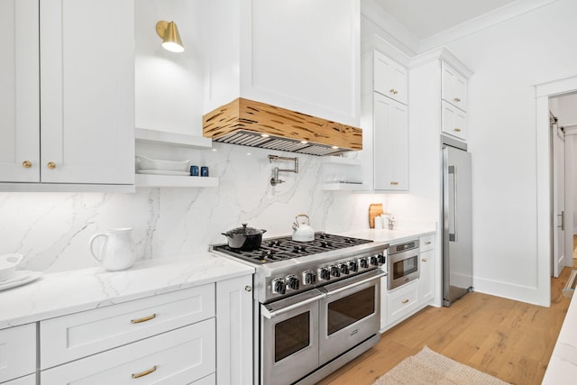 kitchen with tasteful backsplash, light stone counters, high quality appliances, white cabinets, and custom exhaust hood