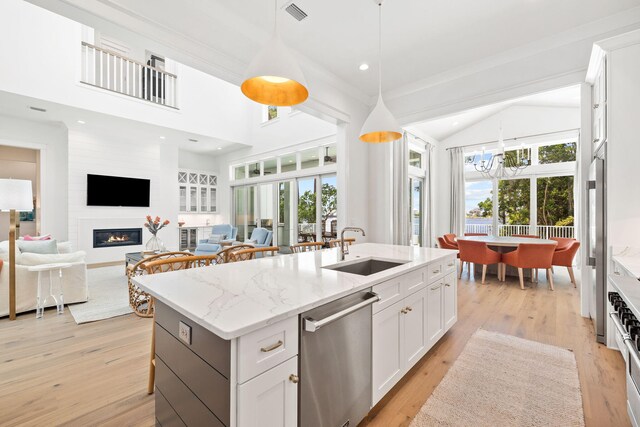 kitchen featuring white cabinets, sink, stainless steel dishwasher, and a kitchen island with sink