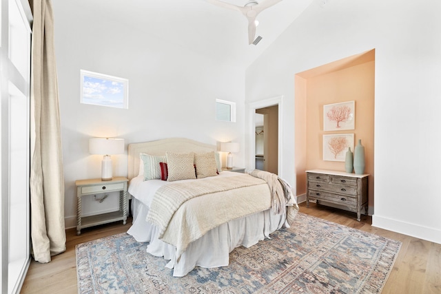 bedroom with ceiling fan, high vaulted ceiling, and light hardwood / wood-style floors