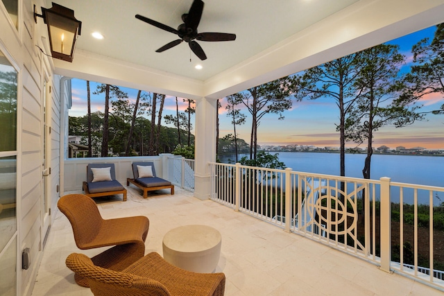 patio terrace at dusk with a water view and ceiling fan