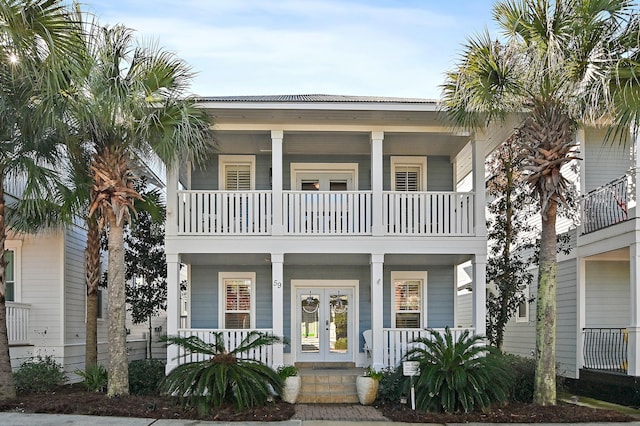 coastal inspired home with a porch, a balcony, and french doors