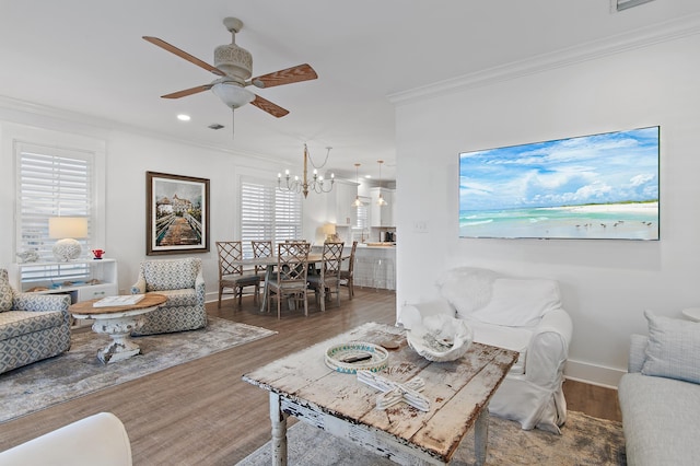 living room with ceiling fan with notable chandelier, hardwood / wood-style flooring, and crown molding