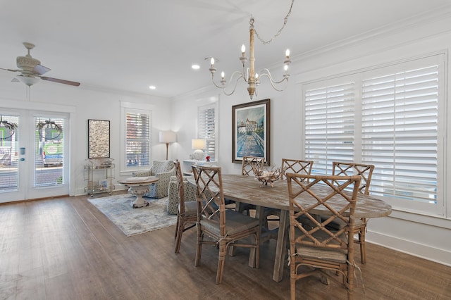 dining room with dark wood-type flooring, ceiling fan with notable chandelier, and ornamental molding