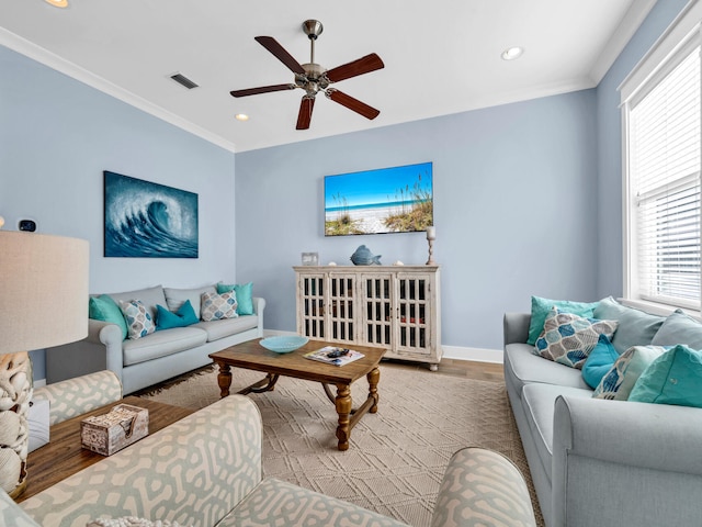 living room featuring ornamental molding, ceiling fan, light hardwood / wood-style flooring, and a wealth of natural light