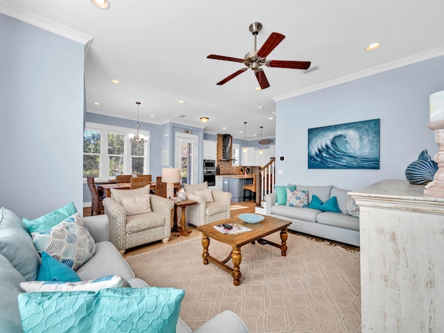 living room with ceiling fan with notable chandelier and ornamental molding