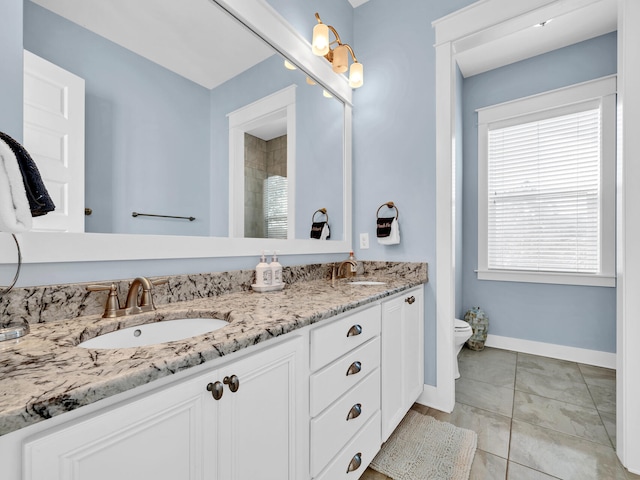 bathroom featuring toilet, tile patterned flooring, vanity, and a healthy amount of sunlight