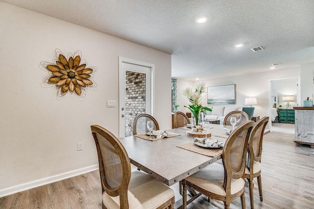 dining space with light wood-type flooring and a textured ceiling