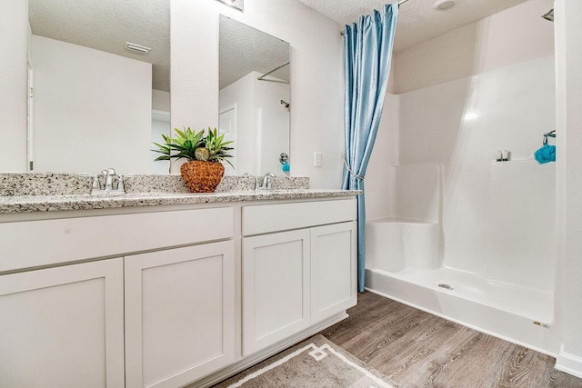 bathroom featuring vanity, wood-type flooring, a textured ceiling, and a shower with curtain