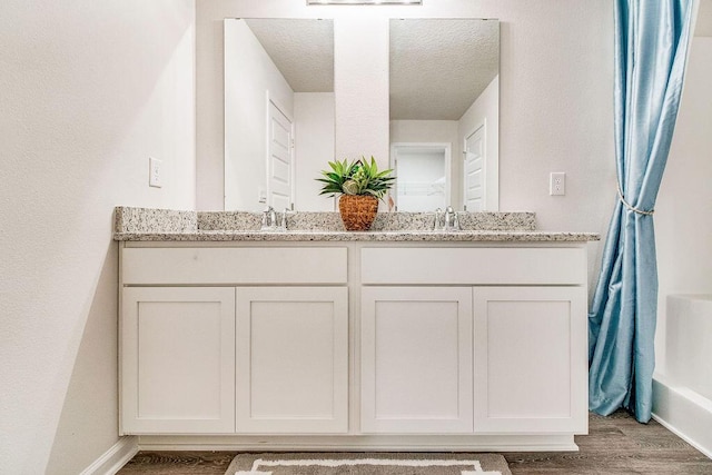 bathroom with hardwood / wood-style floors, vanity, and a textured ceiling