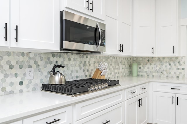 kitchen featuring tasteful backsplash, light stone counters, stainless steel appliances, and white cabinets