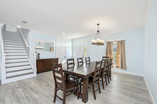 dining room with ornamental molding, a notable chandelier, and light wood-type flooring