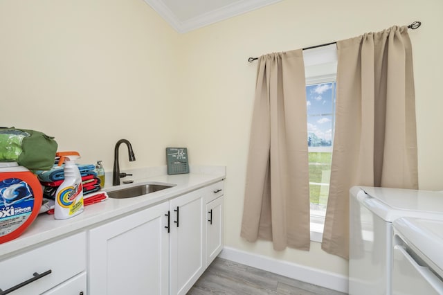 clothes washing area with separate washer and dryer, sink, cabinets, light hardwood / wood-style floors, and crown molding