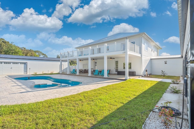 back of property with a garage, a balcony, a yard, an outdoor structure, and ceiling fan