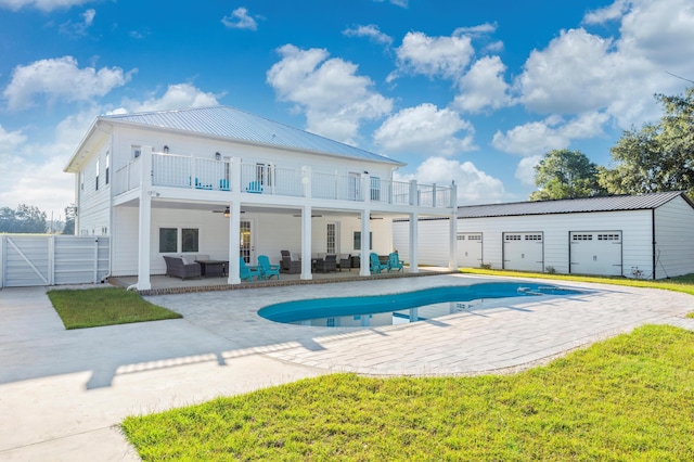 back of house featuring a yard, outdoor lounge area, a patio, an outbuilding, and a balcony