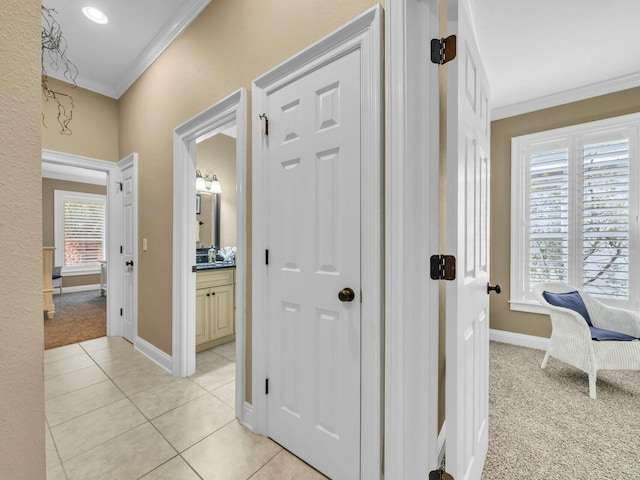 corridor featuring sink, light colored carpet, and crown molding