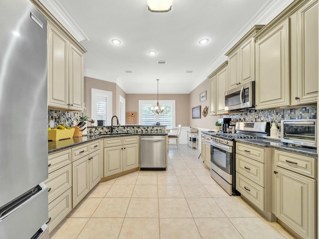 kitchen with pendant lighting, dark stone countertops, stainless steel appliances, and cream cabinetry