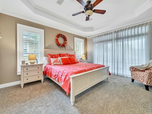 bedroom featuring a tray ceiling, multiple windows, ceiling fan, and light carpet