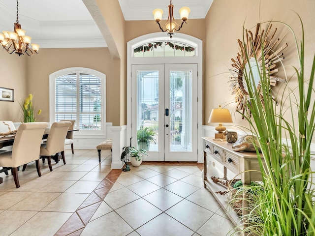 tiled foyer with crown molding, french doors, and a chandelier