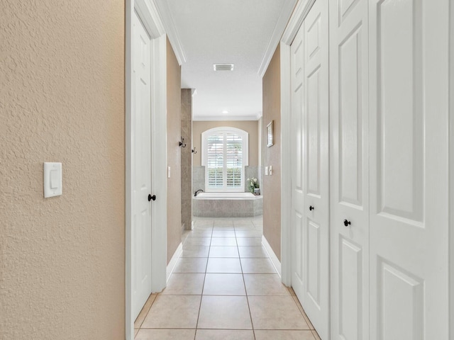 hall with crown molding and light tile patterned flooring