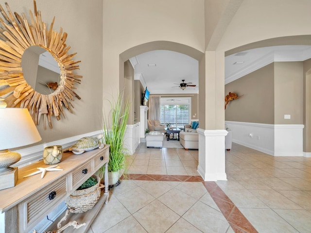 interior space with light tile patterned floors, crown molding, and decorative columns