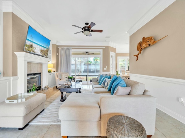 tiled living room featuring ceiling fan, a wealth of natural light, crown molding, and a tile fireplace