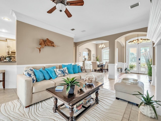 tiled living room featuring crown molding, french doors, and ceiling fan with notable chandelier