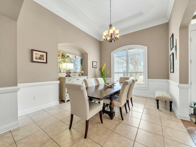 tiled dining space with a raised ceiling, ornamental molding, and a notable chandelier