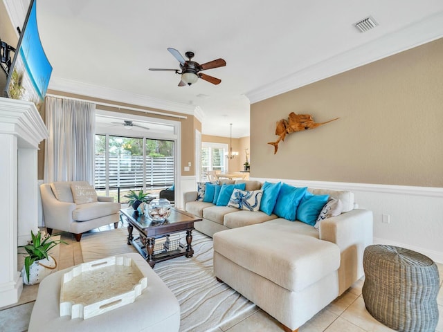 tiled living room with ceiling fan with notable chandelier and crown molding