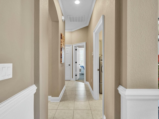 hall featuring light tile patterned floors and crown molding