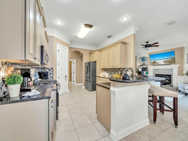 kitchen featuring ornamental molding, appliances with stainless steel finishes, light tile patterned flooring, a kitchen bar, and kitchen peninsula