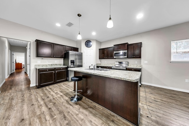 kitchen featuring pendant lighting, a breakfast bar, sink, appliances with stainless steel finishes, and dark brown cabinetry