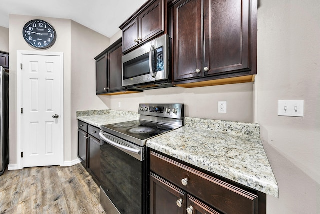 kitchen with light stone counters, dark brown cabinetry, light wood-type flooring, and stainless steel appliances