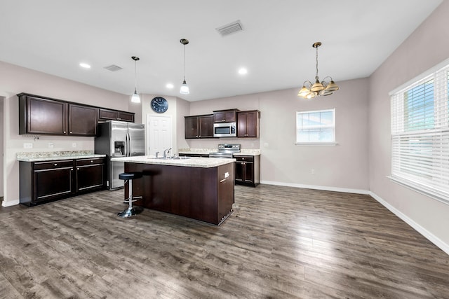 kitchen with a kitchen breakfast bar, sink, hanging light fixtures, and appliances with stainless steel finishes