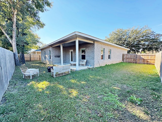 back of house featuring a lawn and a patio area