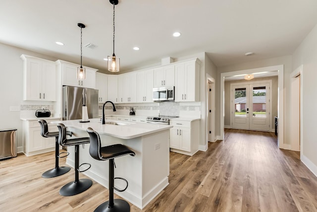 kitchen featuring appliances with stainless steel finishes, white cabinetry, a kitchen island with sink, and sink