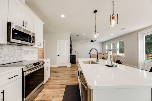 kitchen featuring hanging light fixtures, appliances with stainless steel finishes, a kitchen island with sink, and sink