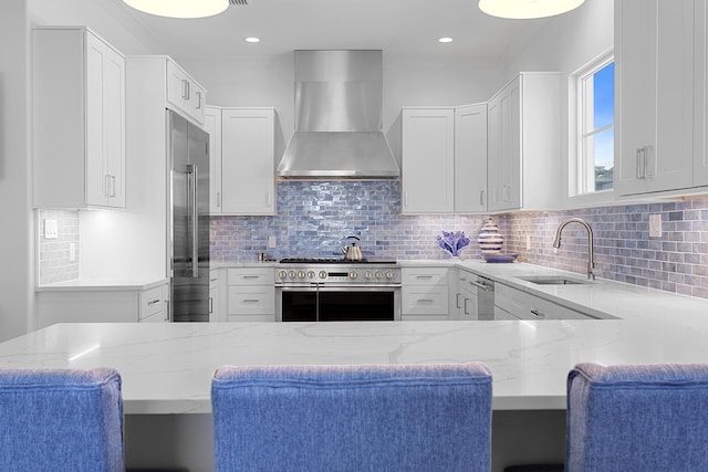 kitchen with white cabinets, high end appliances, and wall chimney exhaust hood