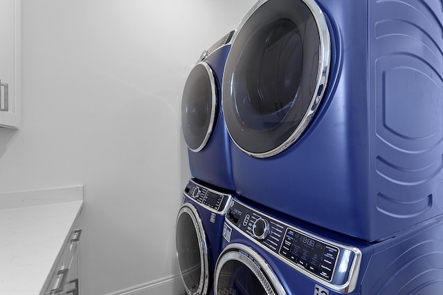 washroom featuring cabinets and stacked washer and dryer