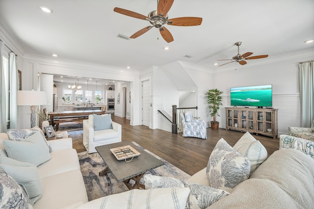 living room with dark hardwood / wood-style floors, crown molding, and ceiling fan with notable chandelier