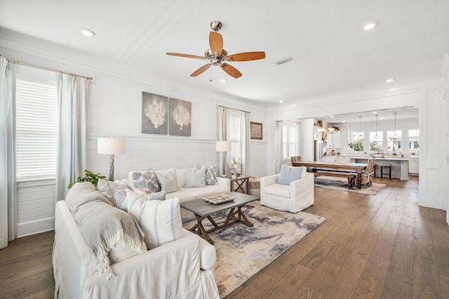 living room featuring dark hardwood / wood-style floors, ceiling fan, and ornamental molding